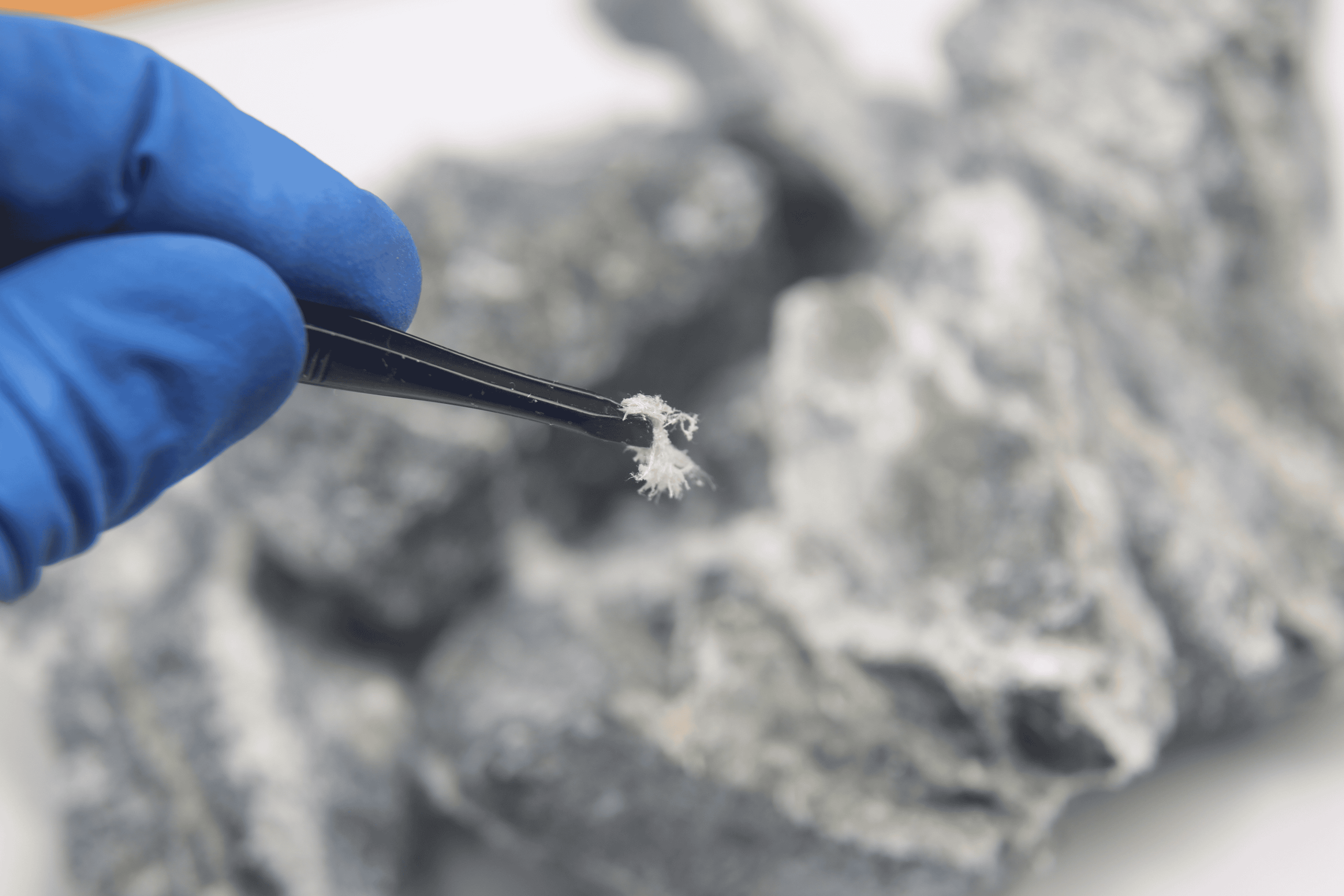A close-up of asbestos between a pair of tweezers.