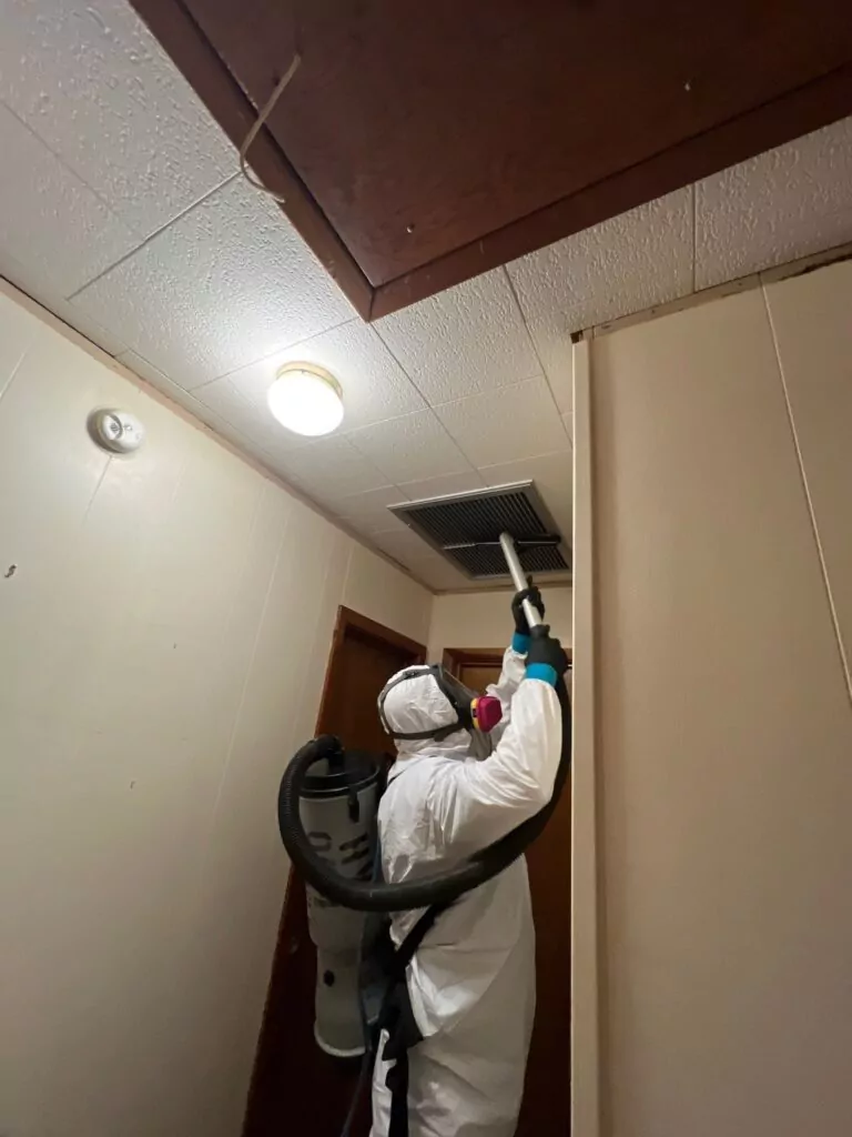 Restoration Pros technician using HEPA vacuum to remove contaminants and microbial particles from affected surfaces during remediation cleaning process.