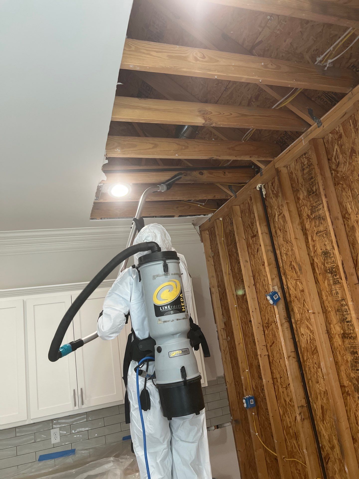 Restoration Pros technician performing professional mold remediation cleaning in kitchen using HEPA vacuuming and antimicrobial treatment solutions.